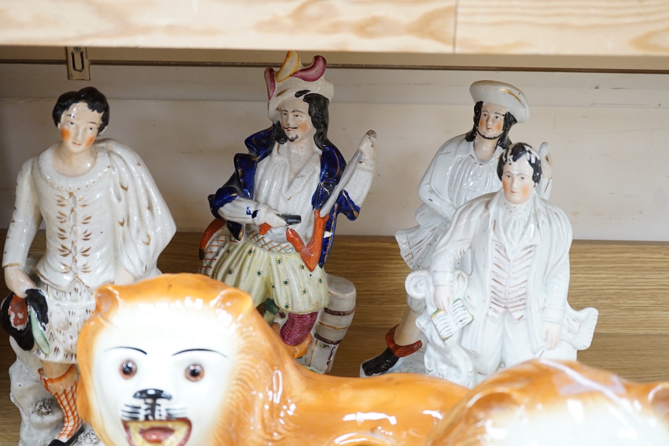 A group of 19th century Staffordshire flat backs and a pair of late Staffordshire pottery lions, 40cms wide